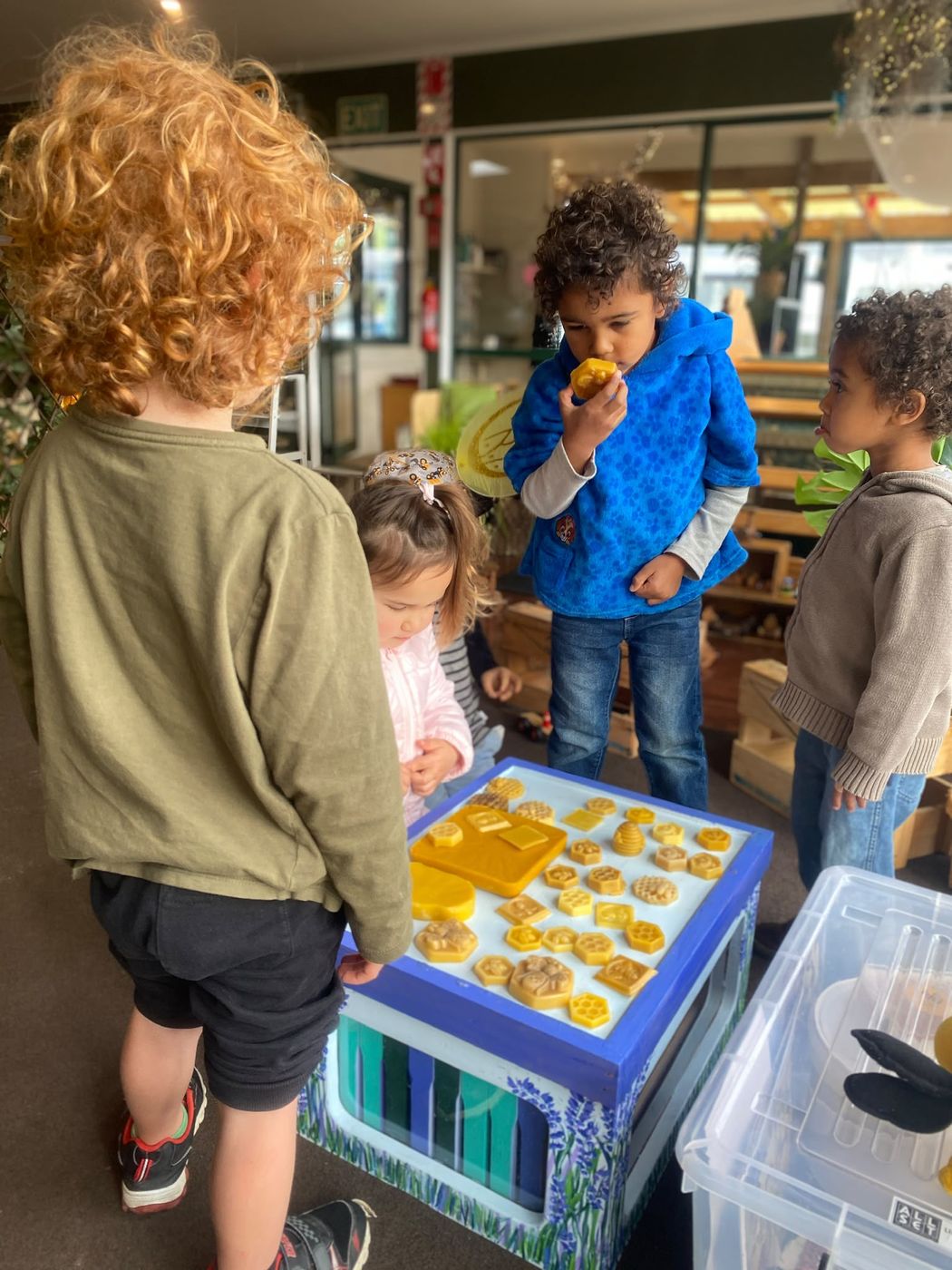 Young children exploring beeswax shapes on a light table