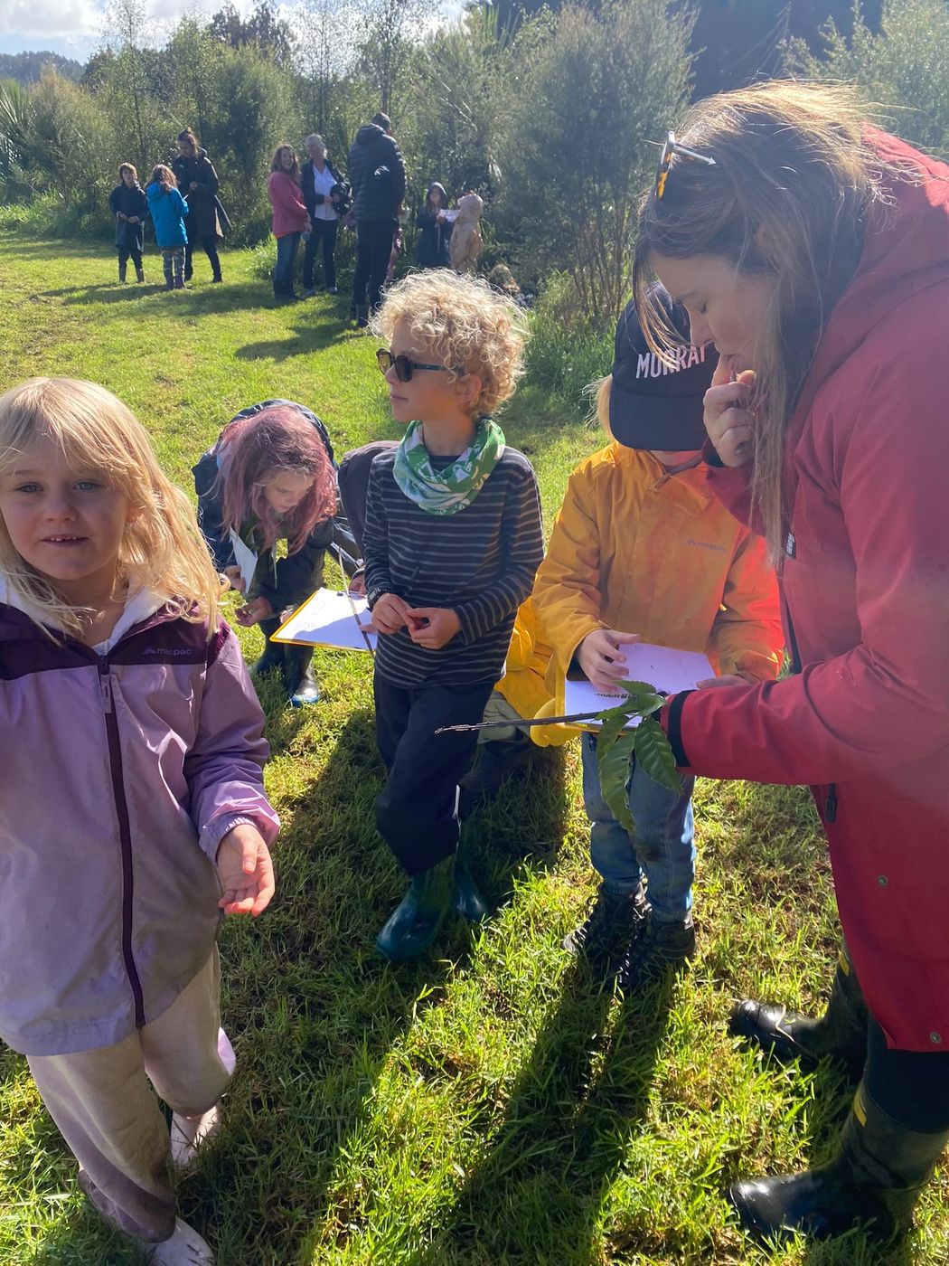 A teacher showing students a leaf during a field walk